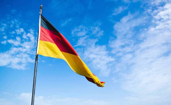 Germany's flag flying on a pole in the blue skies.