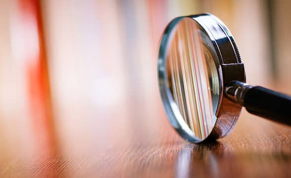 A magnifying glass sitting on a wooden table.