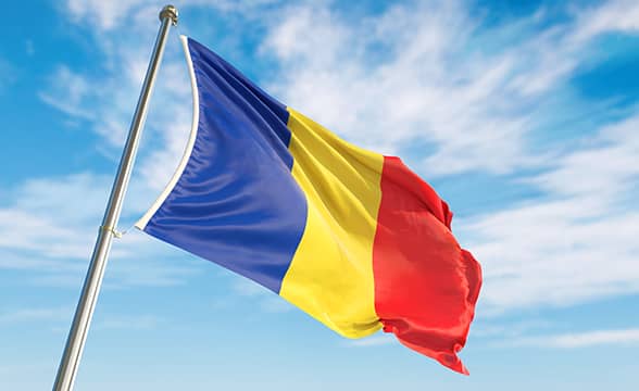 Romania's official country flag on a blue sky.