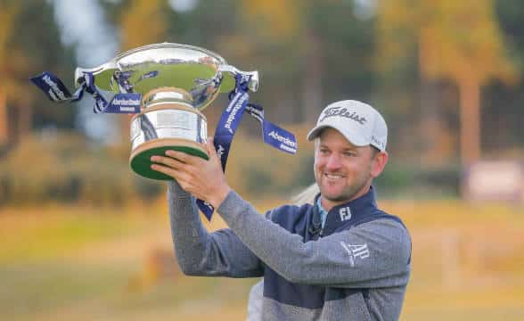 A golfer raising trophy at the Scottish Golf Open.