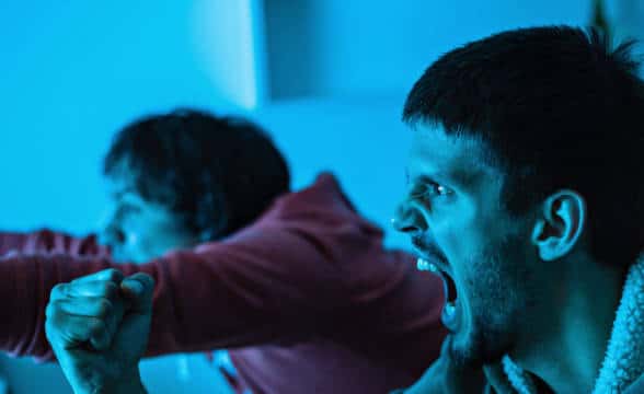 Two sports fans sitting in the dark room and cheering.