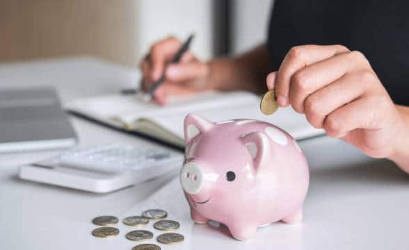 A Piggy bank with coins being put in it.