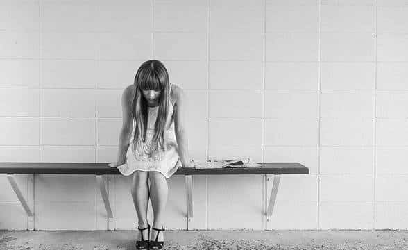 A worried girl sitting on a bench.