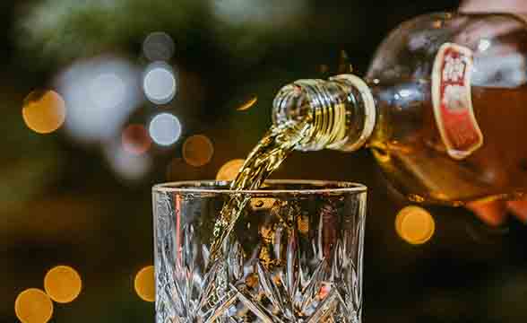 A person pours a glass of liquor