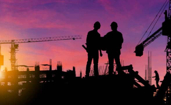 Construction workers at dawn, with only their silhouettes visible against a red dawn and the construction site background.