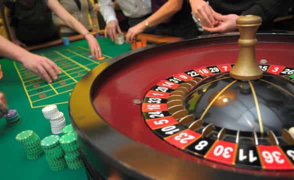 Players and a roulette wheel in a live casino setting.