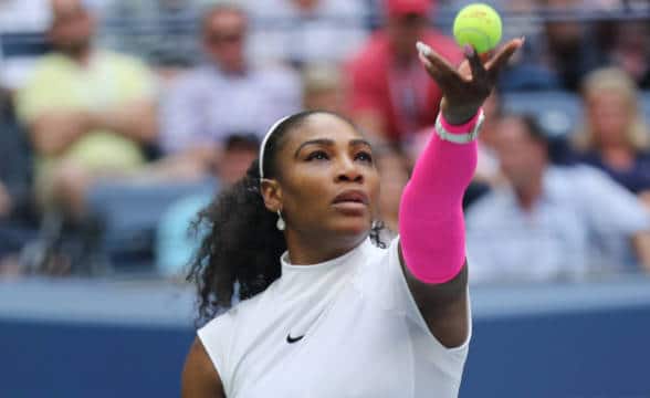 Serena Williams preparing to serve in a game of tennis.