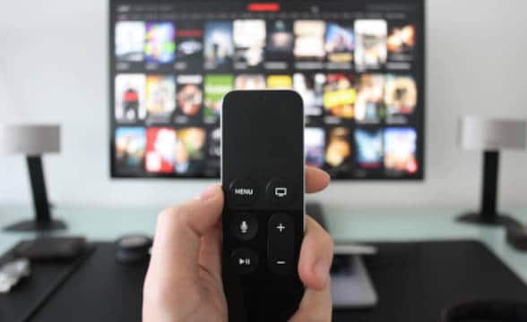 TV and remote controler in a person's hand.