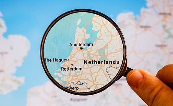 A person uses a magnifying glass to take a look at the map of the Netherlands