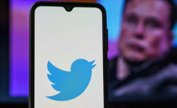 The Twitter logo with a silhouette of Elon Musk in the back.