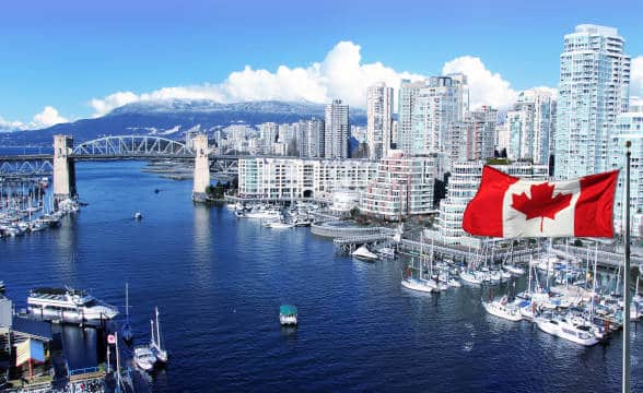 The national flag of Canada against an urban scenery.