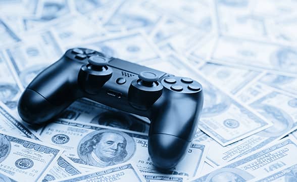 A video game controller sitting on a pile of cash