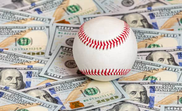 A baseball on top of US dollar bills.