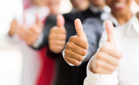 A close up photo of multiple business people giving thumbs up