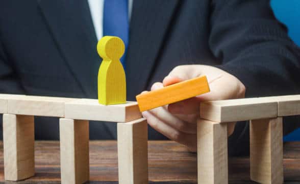 Businessman creating a bridge by placing a tile for a wooden figure