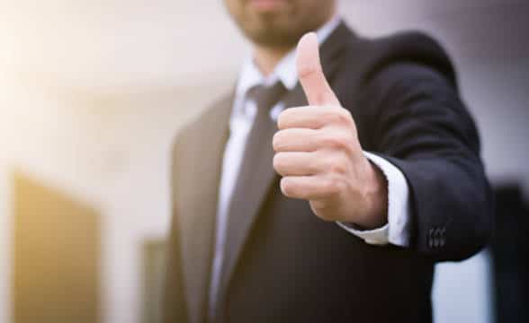 Close up shot of a businessman holding thumb up with one hand