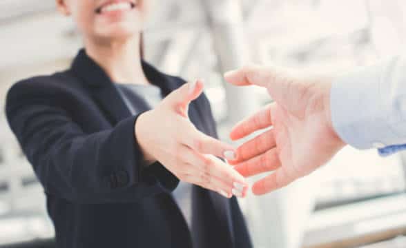 A businesswoman reaching for a handshake with a businessman