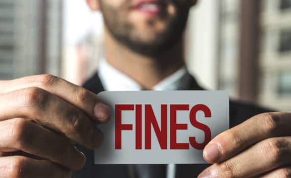 Close up photo of a businessman holding a note with the word fines written on it