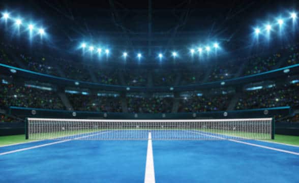 Blue tennis court indoor arena illuminated by lights