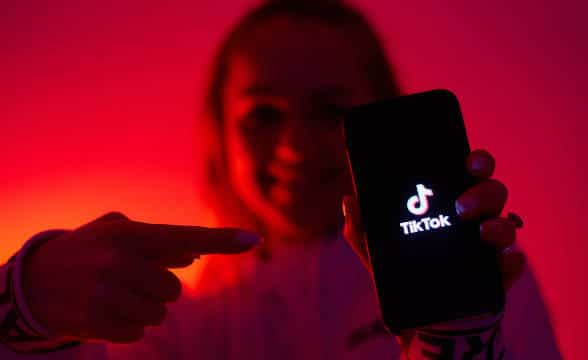 A girl pointing to her TikTok mobile device.