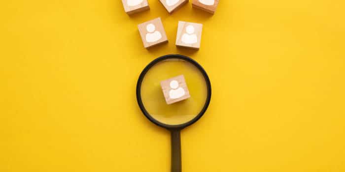 A magnifying glass examining a cube with a person profile on it.