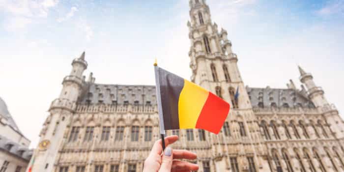 The national flag of Belgium against a backdrop of a national landmark.