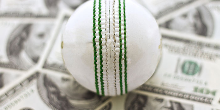 A cricket ball on a pile of dollar bills