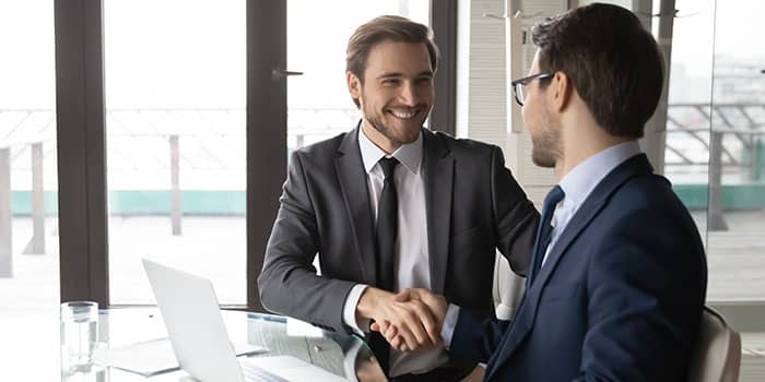 A businessman shakes a hand with a peer