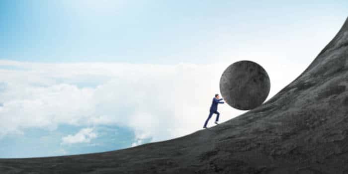 Man pushing a giant rock up a hill