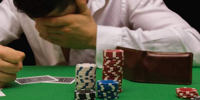 A man holding his face in his palm over gambling losses.