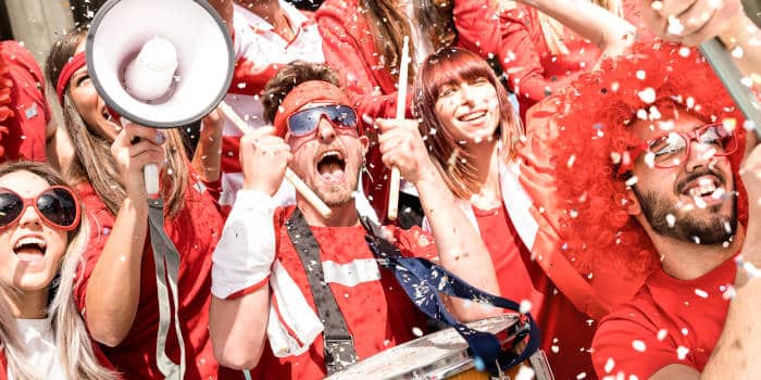 A bunch of fans cheering for their team together and celebrating what might be a win.