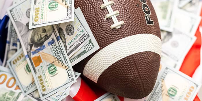 American football ball buried in a pile of money bills