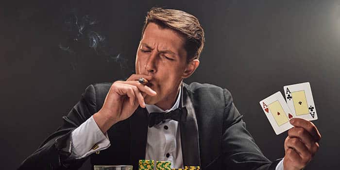 A smoking casino player holding two aces