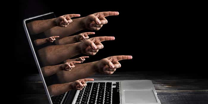 Online harassment represented by pointed fingers coming out of a screen