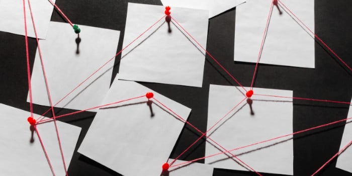 White notes pinned on a blackboard connected with a red string