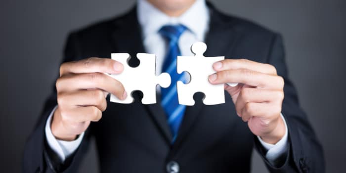 Close up photo of the hands of a businessman holding matching puzzle pieces