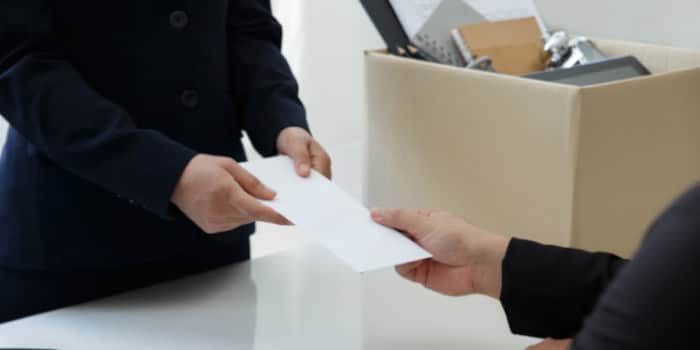 A businessman handing a layoff notice to a female employee