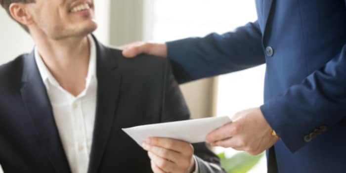 A businessman giving an envelope to another businessman