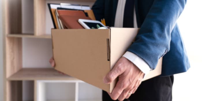 A businessman holding a cardboard box full of personal belongings, symbol for resignation