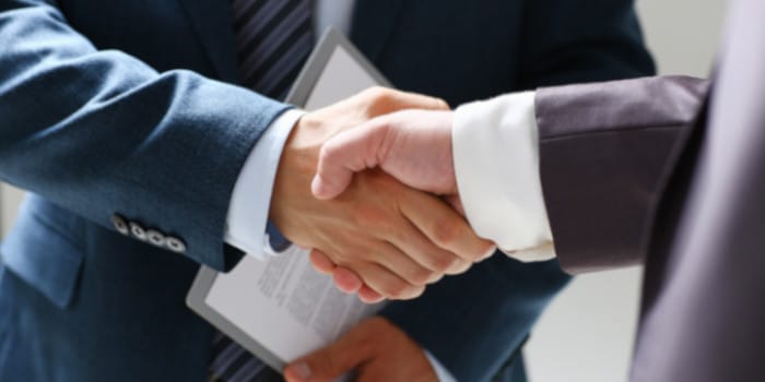 A businessman holding a folder shaking hand with another businessman