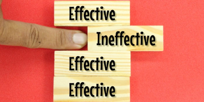 A finger pushing wooden piece with the word ineffective on it amid a row of cubes