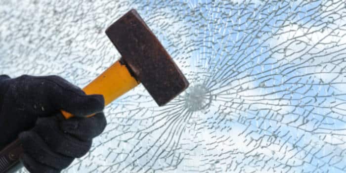 Hand with a hammer breaking a window