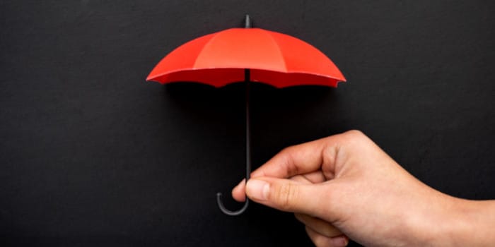 Close up photo of a hand holding a tiny red umbrella