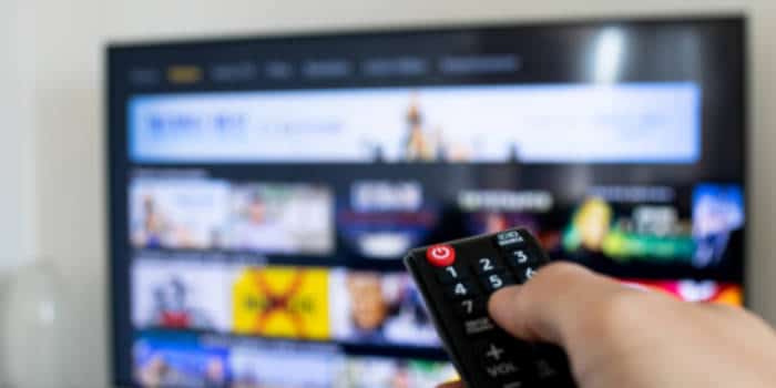 A close up photo of a hand holding a TV remote control