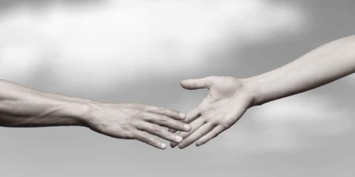 Close up photo of a woman's hand reaching for the hand of a man