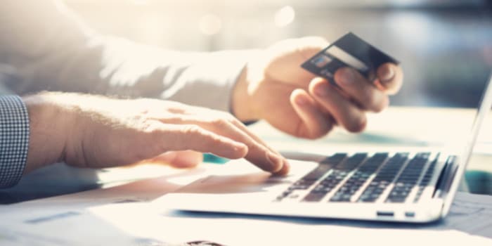 Man holding credit card entering details via computer