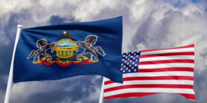 Pennsylvania flag waving in the air next to a US flag