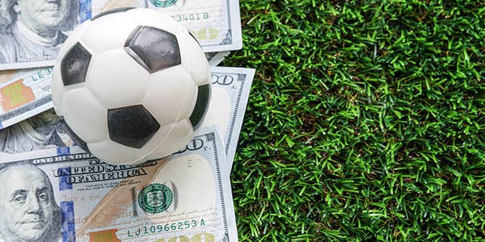 A soccer ball on top of a pile of cash