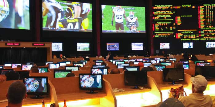 A sports betting lounge with punters sitting in chairs and watching the games.