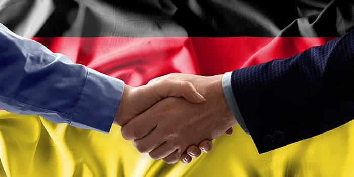 Businessmen shake hands in front of the German flag